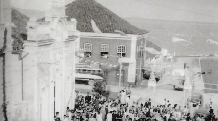 Grupo de pessoas visto de cima passa por uma rua de praça, em foto preto e branco