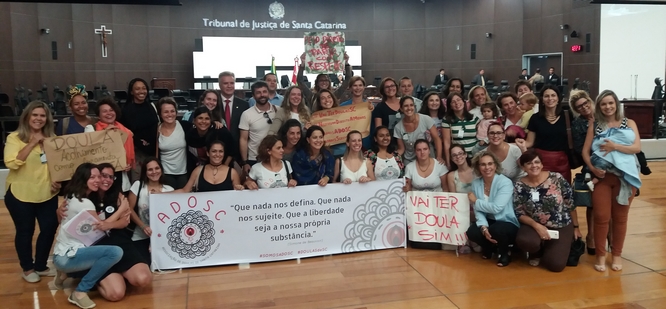 Grupo de mulheres posa para foto com uma faixa escrita "Que nada nos defina"