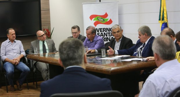 Mesa de reunião com políticos em apenas um lado para coletiva de imprensa