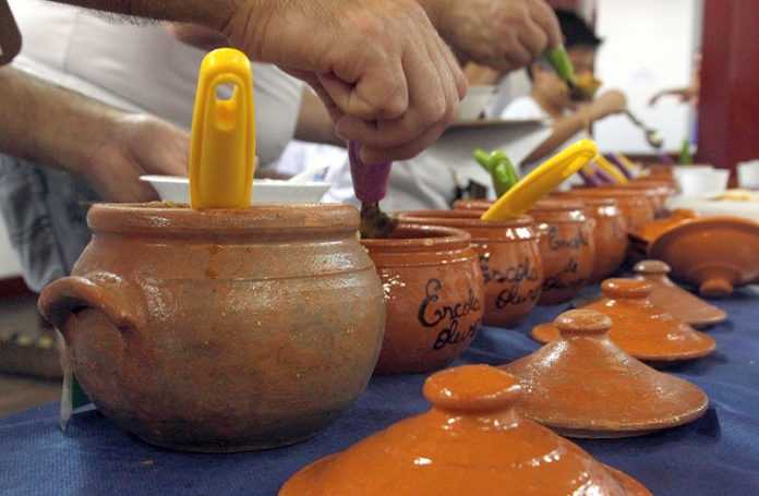 Close nos potes de barros enfileirados em que as pessoas se servem de sopa