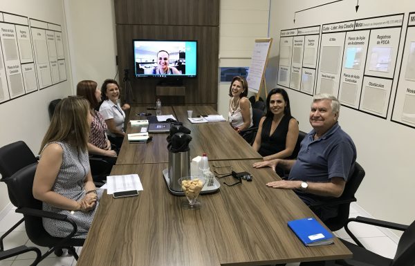 Grupo de oito pessoas em uma sala de reuniões, sentado em volta de uma mesa