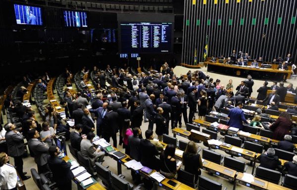 Vista do salão do Senado, com muitas cadeiras e pessoas engravatadas em pé pelo ambiente