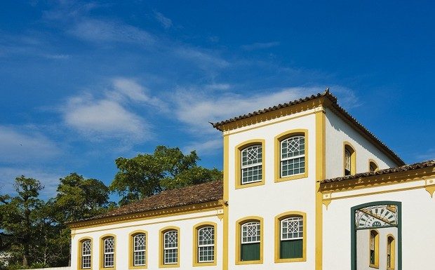 Imagem da fachada do museu; construção estilo açoriana: paredes em branco com janelas verdes