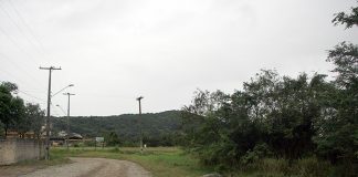 rua de paralelepídeos antiga que faz uma curva à esquerda com um terreno baldio em volta