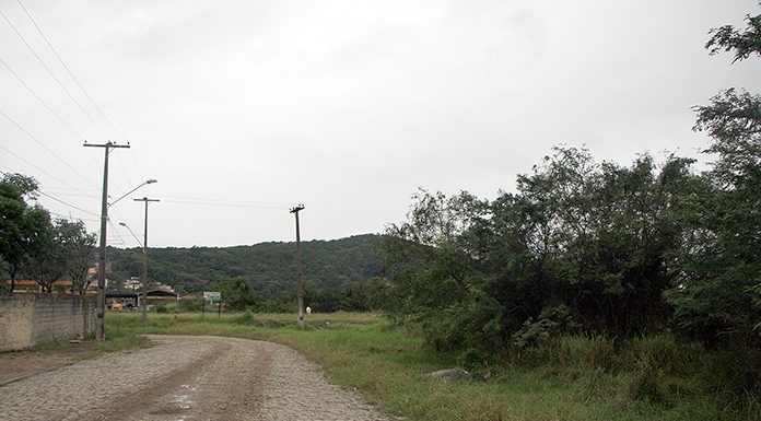 rua de paralelepídeos antiga que faz uma curva à esquerda com um terreno baldio em volta