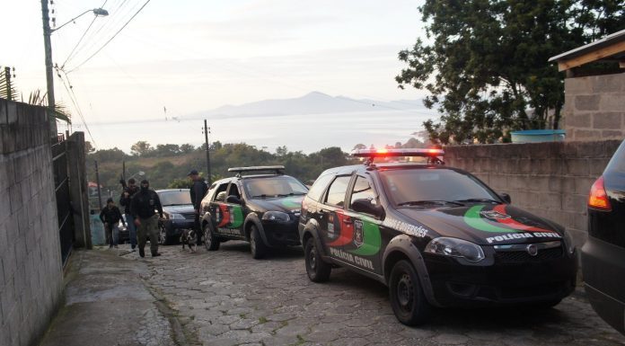 ladeira estreita de paralelepípedos com carros da polícia civil estacionados e agentes usando balaclava e armamento pesado