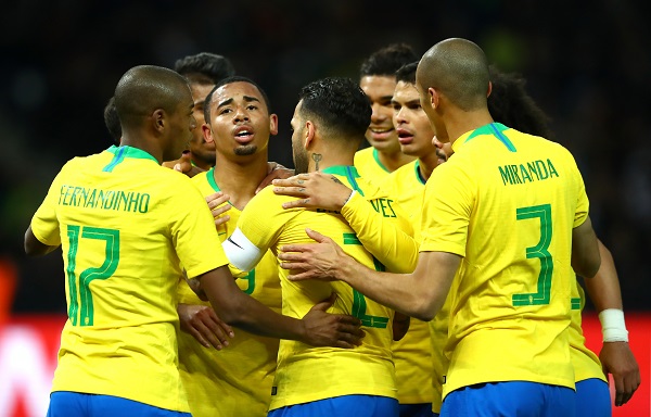 Jogadores da seleção abraçados comemorando um gol; de costas Fernandinho e Miranda