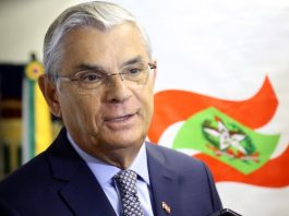 Governador de Santa Catarina Eduardo Pinho Moreira posa para foto em frente a bandeira do estado