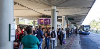 pessoas esperam ônibus em plataforma