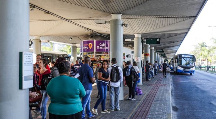 pessoas esperam ônibus em plataforma