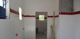 corredor em obras com porta ao fundo e paredes com lajotas