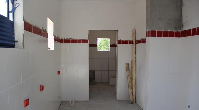 corredor em obras com porta ao fundo e paredes com lajotas