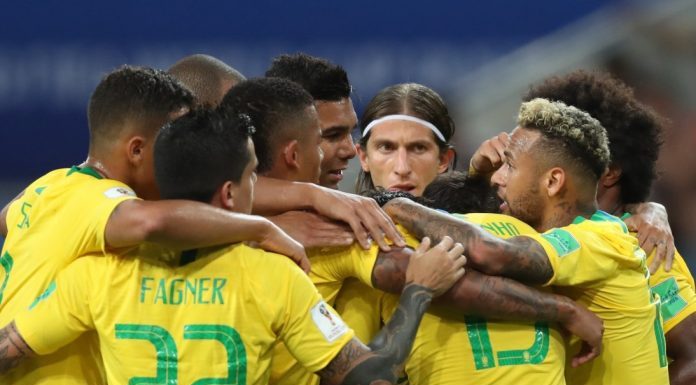 Jogadores da seleção, usando uniforme, se abraçam em grupo