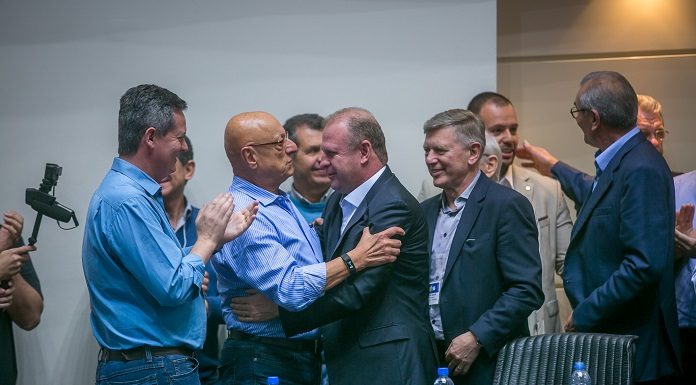 amin e merisio se cumprimentam sorridentes ao centro da fotos, com outros homens em volta