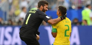 dois jogadores de brasil ajoelhados no gramado; goleiro brasileiro pega na cabeça do zagueiro thiago silva; estão comemorando