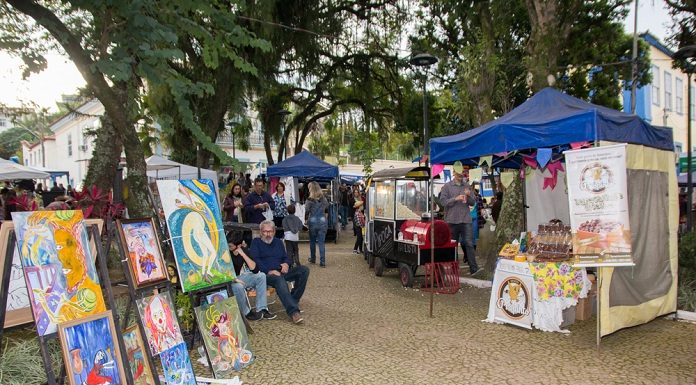 barracas de feiras com diversos produtos expostos; na esquerda, quadros