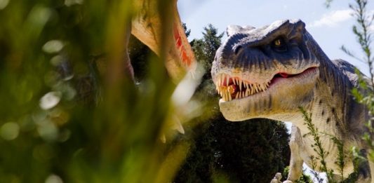 reproduçaõ realista de um dinossauro carnívoro no meio da vegetação