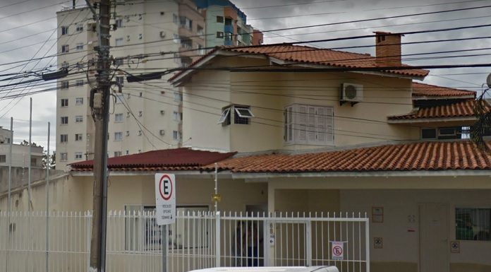 fachada da casa sede do igp em são josé; portão de grade e um poste na frente com muitos fios; alguns carros estacionados