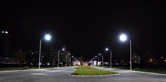 avenida larga, com canteiro central, vista vazia de noite com postes novos acesos