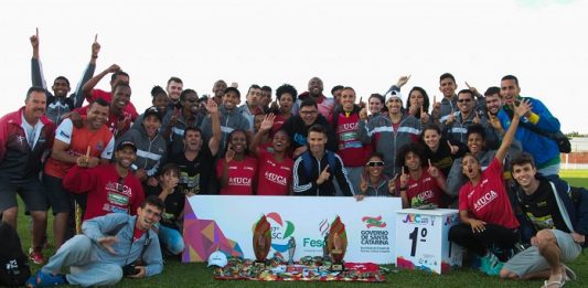 grupo de atletas posa mostrando medalhas em um gramado