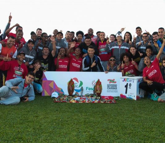 grupo de atletas posa mostrando medalhas em um gramado