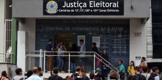 pessoas em fila na frente de cartório da justiça eleitoral para fazer cadastro biométrico