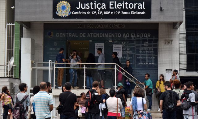 pessoas em fila na frente de cartório da justiça eleitoral para fazer cadastro biométrico