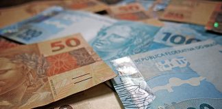 notas de 50 e 100 reais dispostas sobre uma mesa