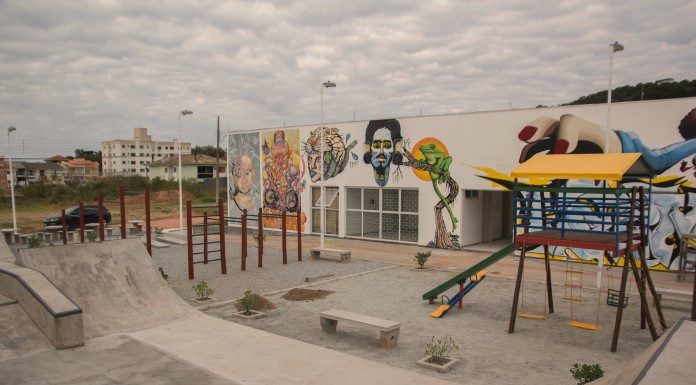 área da praça com pista de skate, parquinho e prédio ao fundo