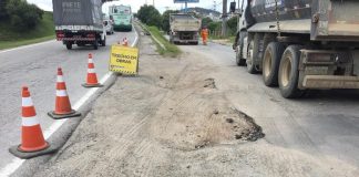 trecho de areia entre duas vias de asfalto com sinalização de cones e caminhões estacionados