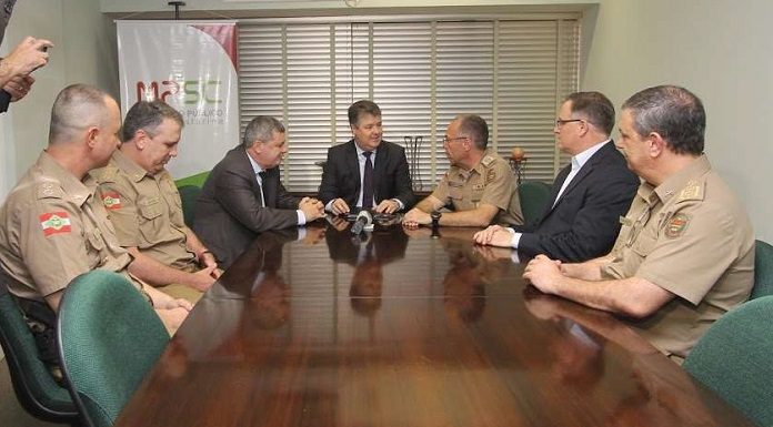 policiais reunidos com membros do mp em uma grande mesa de madeira