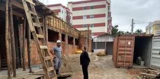 ao lado de prédio em construção, prefeita adeliana conversa com um operário, usando capacete