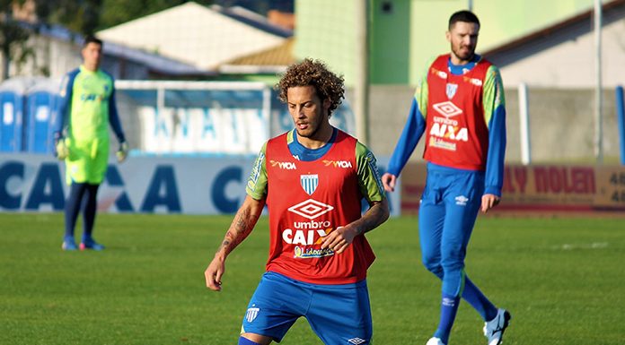 jogador guga em treino do avaí carrega a bola, observado por outros jogadores ao fundo