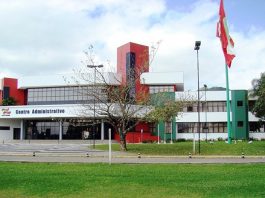 fodo do prédio sede do governo, com gramados e árvores na frente e a bandeira de sc