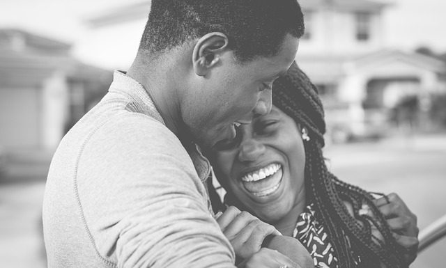 homem e mulher negra se abraçam sorridentes em foto preto e branco