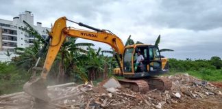 operário em retroescavadeira sobre escombros em área do parque