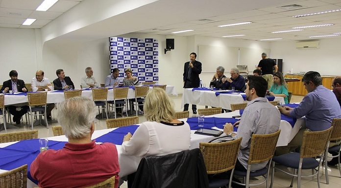 diversas pessoas em reunião em volta de uma grande bancada