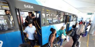 pessoas descendo de um ônibus do tranporte coletivo no terminal de passageiros