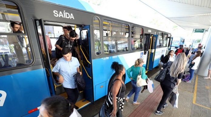 pessoas descendo de um ônibus do tranporte coletivo no terminal de passageiros