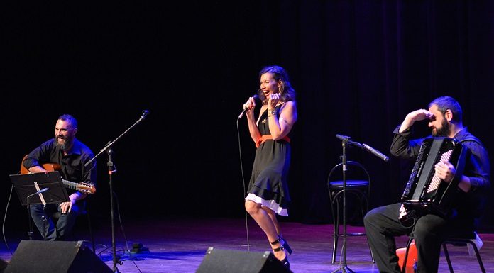 trio no palco; bia está em pé no meio dando risada