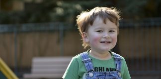 menino brinca sorridente em um parquinho