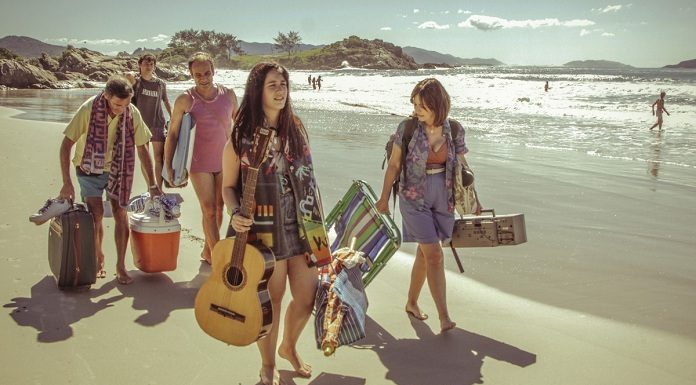 cena do filme em que as pessoas estão andando na praia carregando malas de viagem