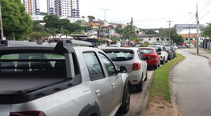 carros estacionados ao longo de uma rua e ao lado de uma ciclovia