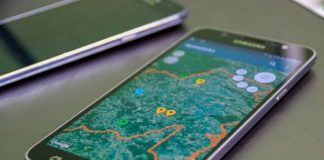 smartphone sobre uma mesa com um mapa de uma cidade na tela e pontos marcados