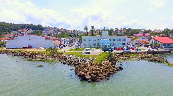 foto aérea, de cima do mar em direção ao continente, mostrando a orla do centro, com predio da camara no meio, ginásio e praças ao fundo