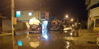 dois caminhões parados no meio de rua alagada à noite