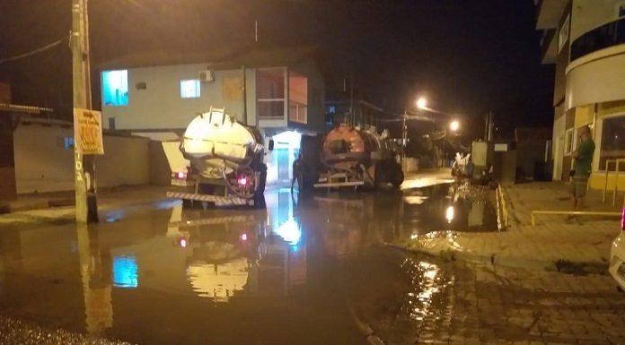 dois caminhões parados no meio de rua alagada à noite