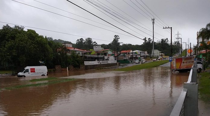 grande área alagada bem no meio da avenida das torres; carros ilhados ao fundo e uma van tentando passar pela água