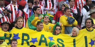 torcedores do brasil usando uma camisa larga que envolve todos, o da esquerda é o "gaúcho da copa"