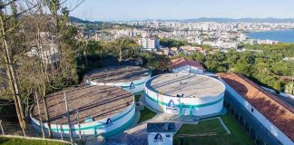 imagem superior de três grandes reservatorios de água circulares da casan do no alto de um morro e a cidade ao longe